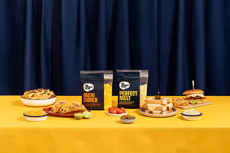 Perfect Melt and Mexi Shred packs with loaded dishes on a yellow table